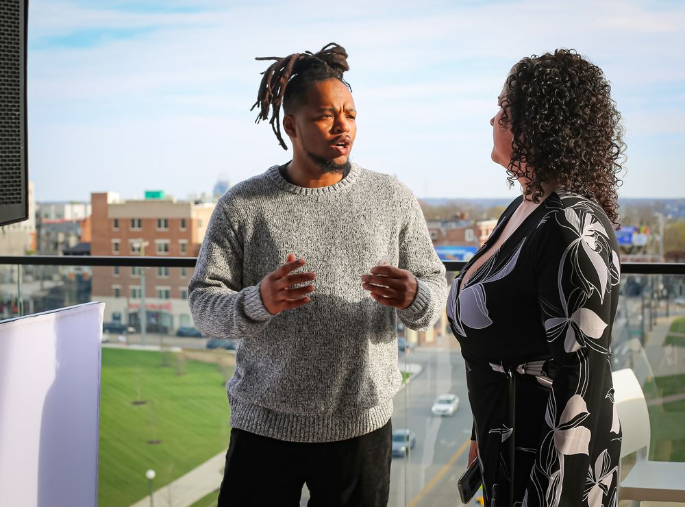 Two people having a professional conversation while standing on a balcony overlooking a city view.