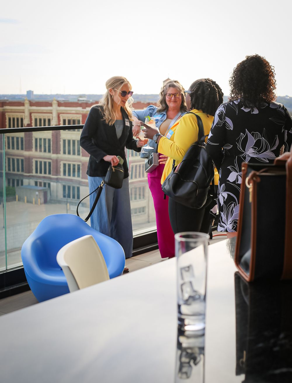 People socializing at a rooftop lounge with city views and modern blue furniture.