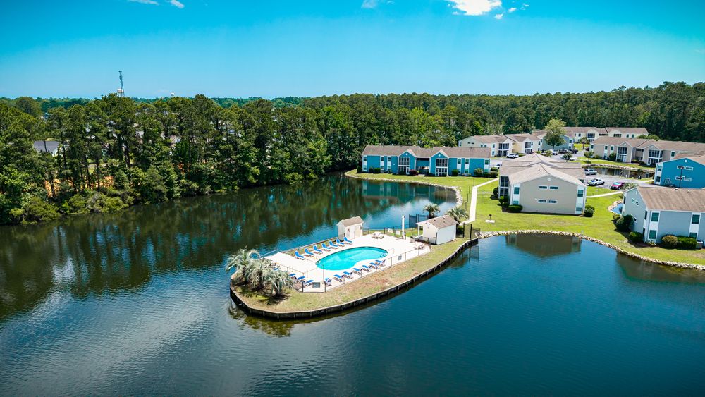 Resort-style swimming pool and amenity area on peninsula surrounded by water and apartment buildings.