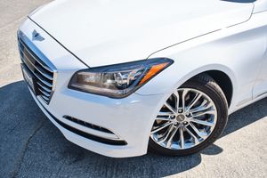 Close-up view of the front quarter panel of a white Hyundai Genesis showing the headlight and wheel design.