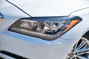 Modern car headlight detail with sleek LED design on pearl white exterior panel surface.