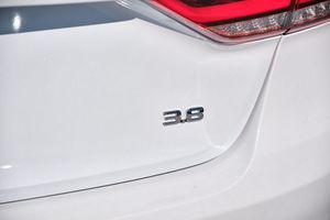 Close-up detail shot of a 3.8 badge emblem on a white car exterior panel.