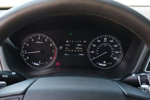 Modern vehicle instrument cluster showing analog speedometer and tachometer gauges with digital display in center.