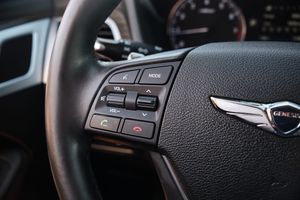 Genesis steering wheel with multimedia controls and Genesis wing logo.