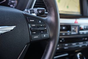 Close-up of steering wheel controls showing cruise control buttons on a Genesis luxury vehicle.