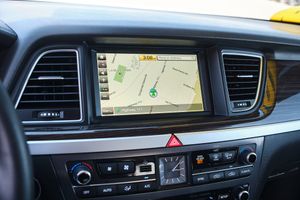 Modern car dashboard display showing GPS navigation system with digital map interface and climate controls.