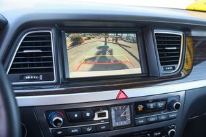 Car dashboard display showing backup camera view with climate controls below.