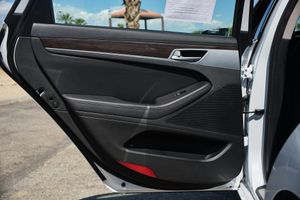 Interior door panel of a Genesis sedan showing black leather trim and modern design elements.