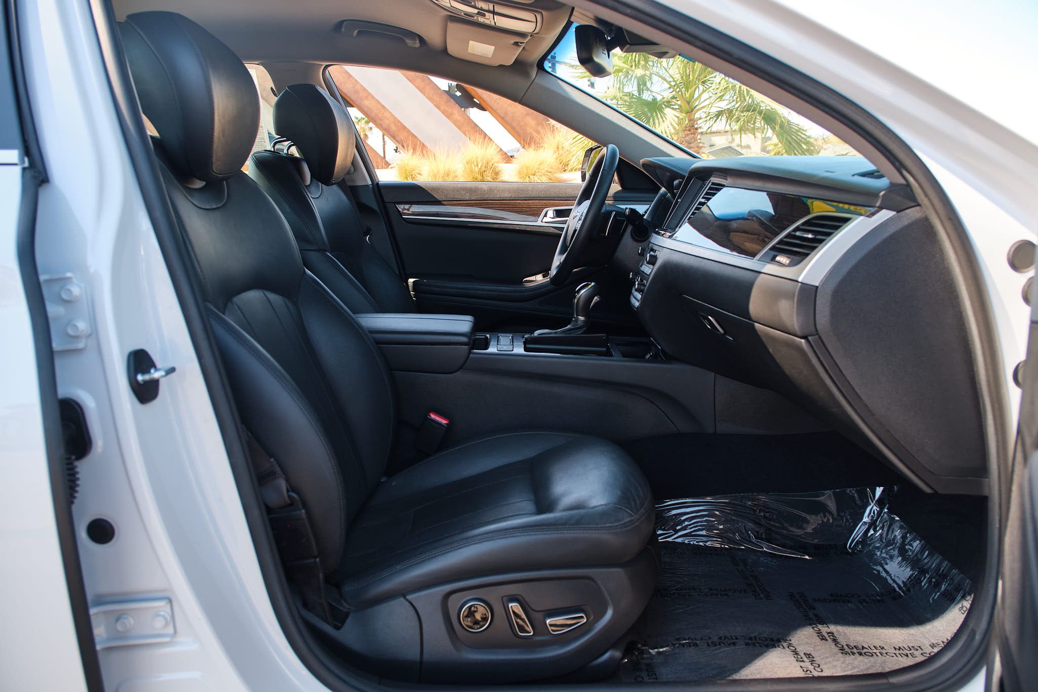 Front seats of a Genesis luxury vehicle showing power-adjustable black leather seats and center console.