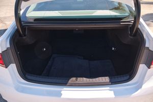 Clean and spacious trunk compartment of a white sedan with carpeted floor and wide opening.