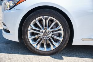 Chrome alloy wheel with multi-spoke design mounted on a white luxury car with black tire visible.