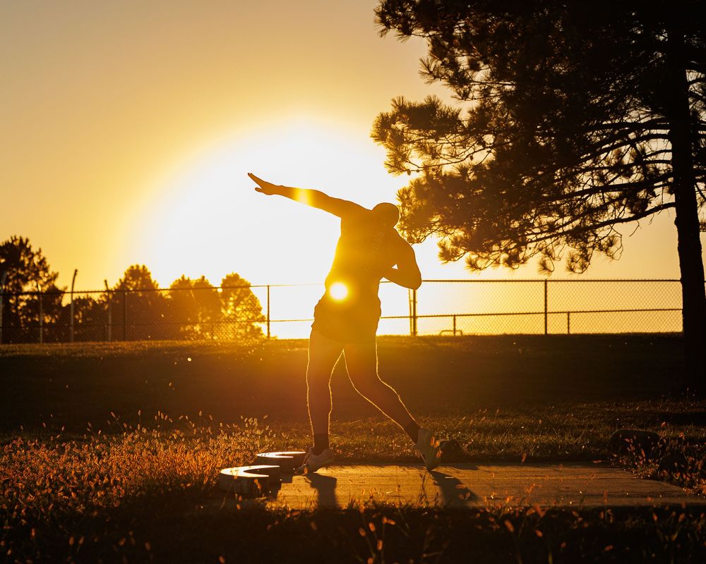 Silhouette of a skateboarder performing a trick against a vibrant golden sunset sky.