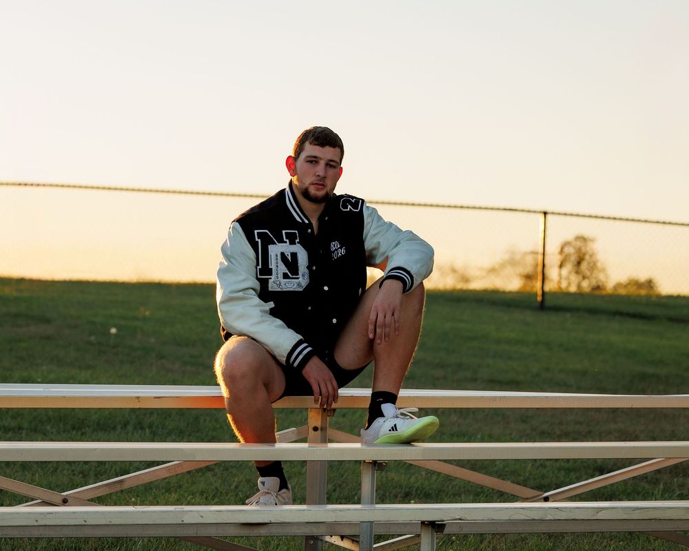 Panoramic sequence of someone sitting on a wooden fence at sunset in a rural field.