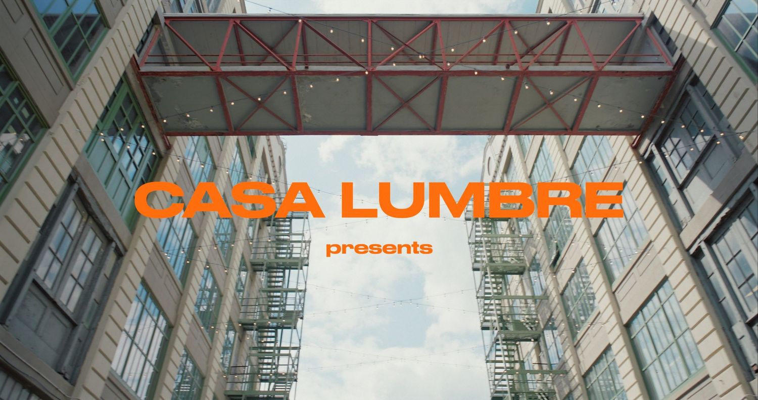 Industrial building exterior with orange text overlay reading 'CARA LUMENS'.