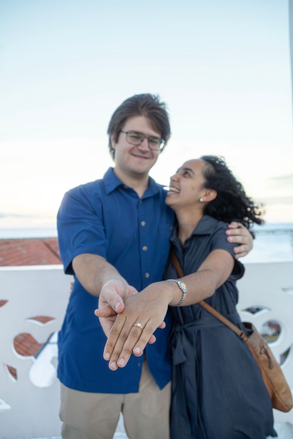 Happy couple showing engagement ring while embracing outdoors.