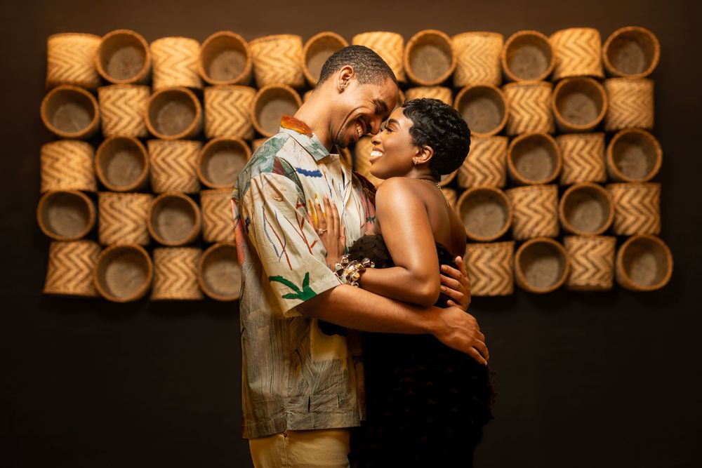 Couple embracing in romantic pose against decorative wooden wall backdrop.