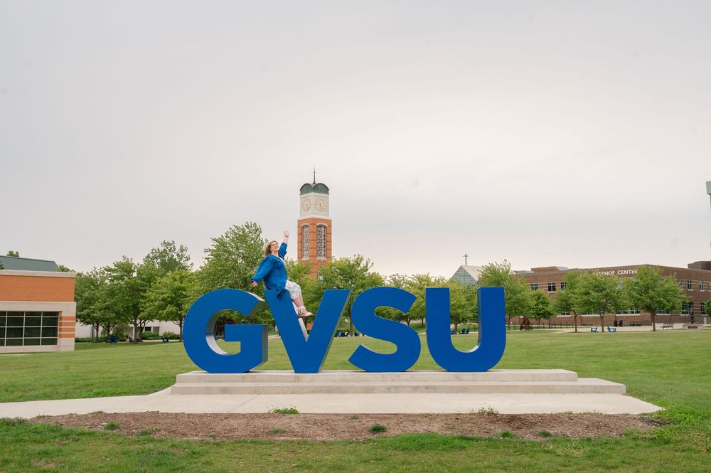 GVSU letters with grad sitting on them
