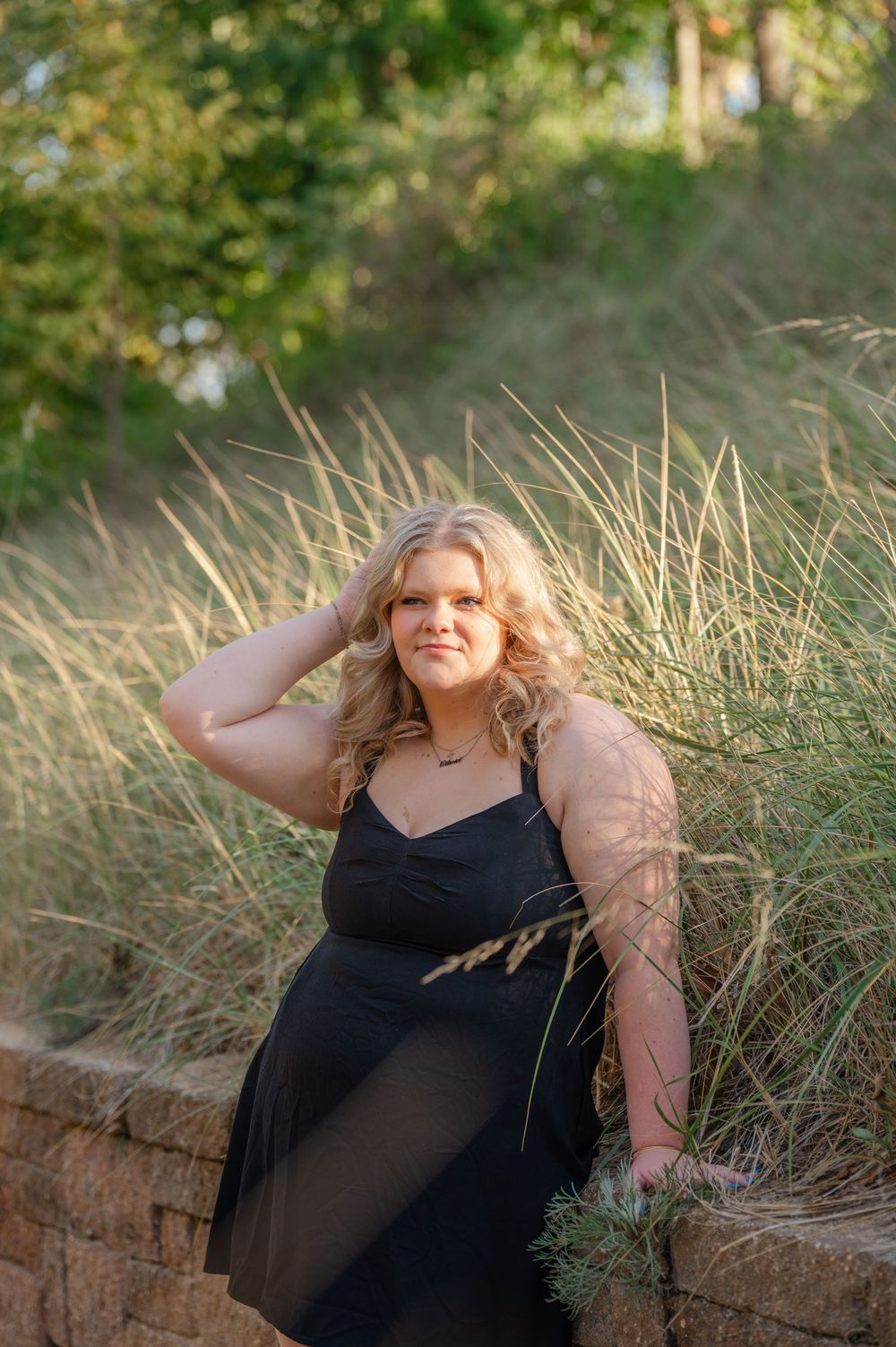 senior sitting on brick wall hand in her looking the other way