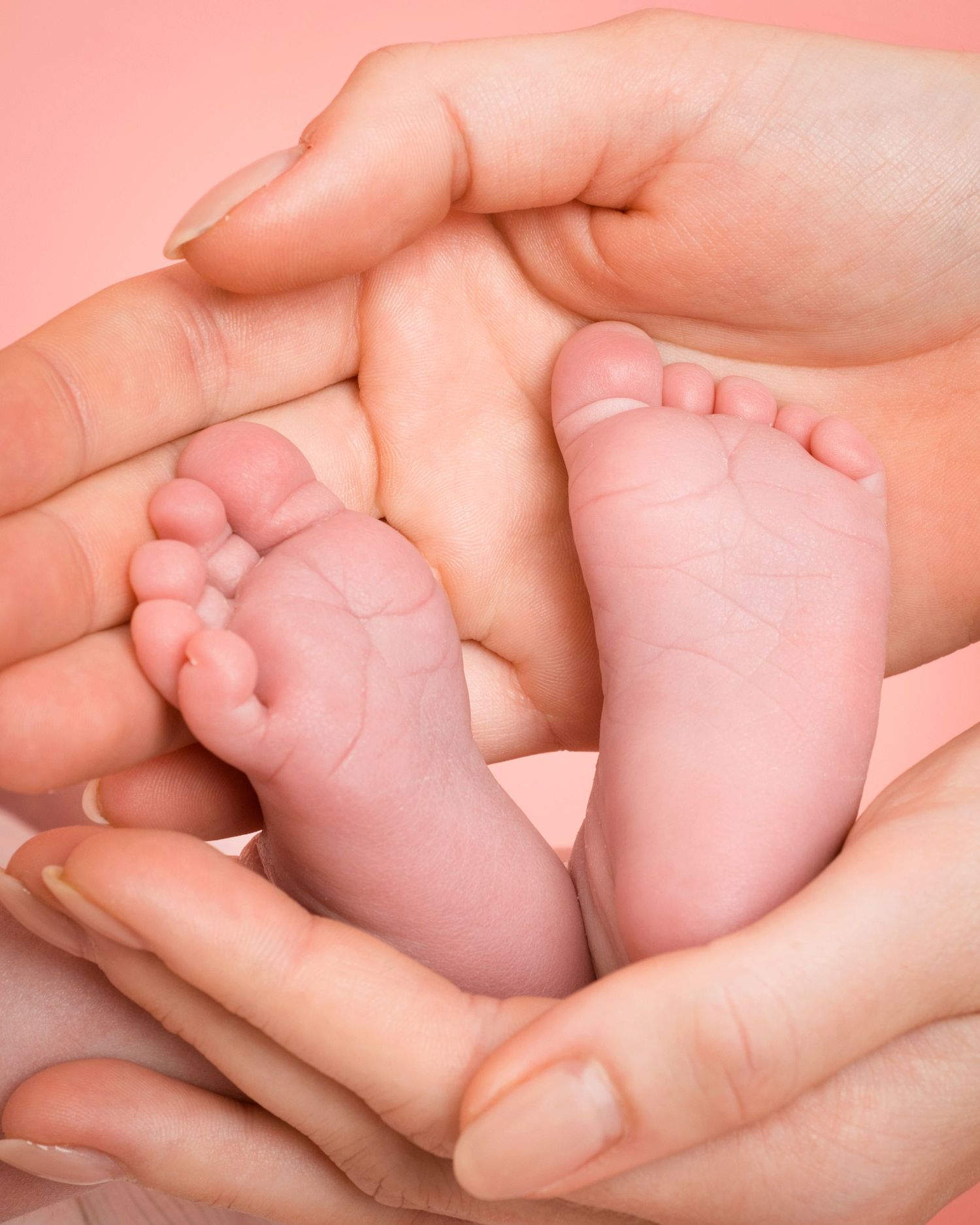 Hands lovingly hold a baby's small feet, capturing the essence of new life in a tender moment. Photography by Abigail's Studio.