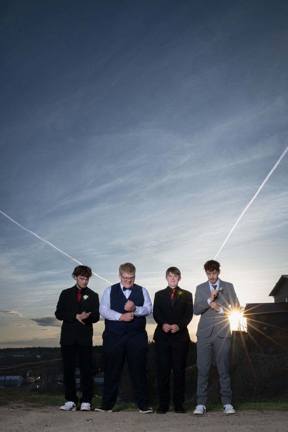 Friends in elegant prom attire pose outdoors at sunset, bathed in warm golden light, capturing joy and unforgettable memories.
