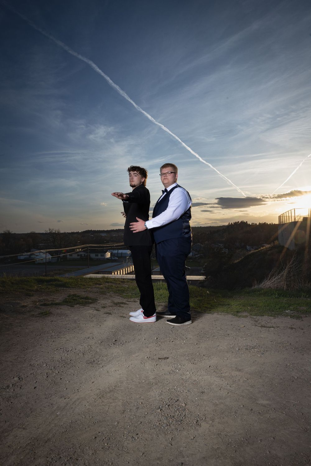 Friends in elegant prom attire pose outdoors at sunset, bathed in warm golden light, capturing joy and unforgettable memories.