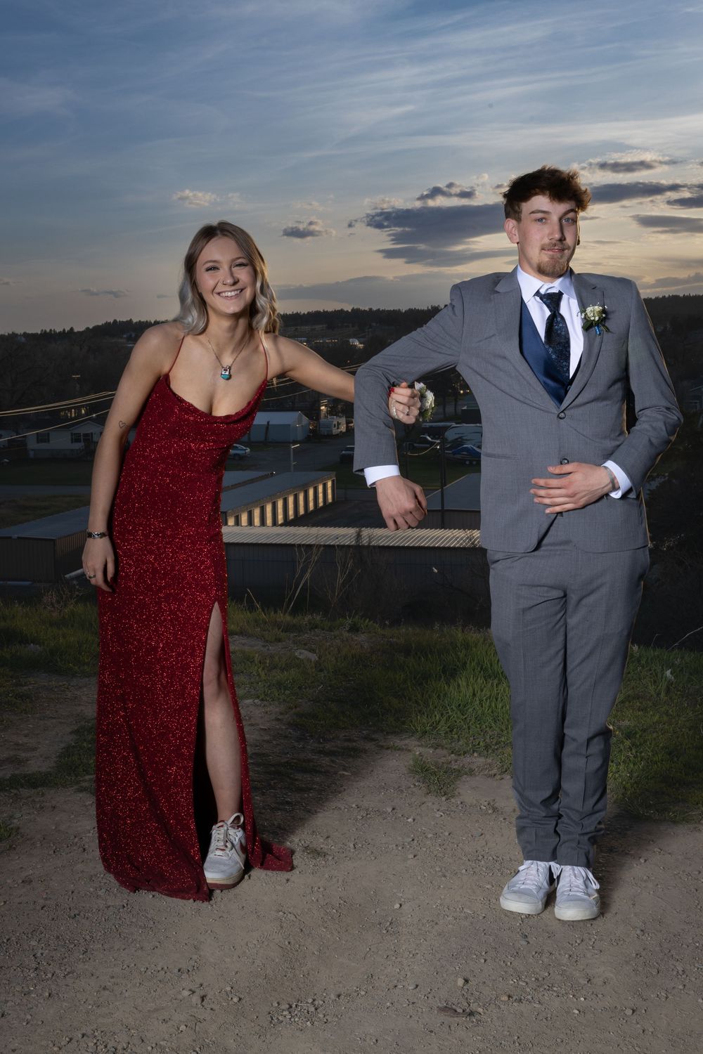 Cousins in elegant prom attire pose outdoors at sunset, bathed in warm golden light, capturing joy and unforgettable memories.
