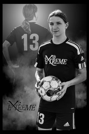 A black and white sports portrait of a soccer player in an Extreme team jersey holding a ball with number 13.