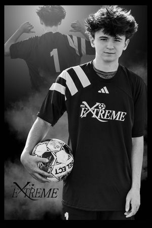 Black and white portrait of a soccer player in an Extreme adidas jersey holding a ball against a dark background.