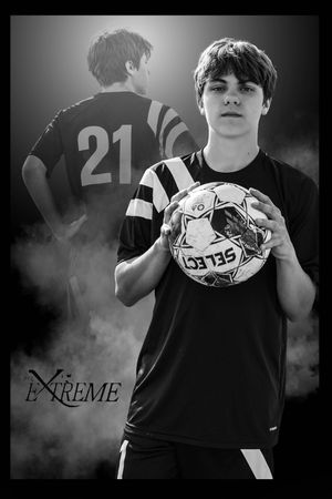 A young soccer player in a black jersey with number 21 poses with a ball in a black and white artistic portrait.