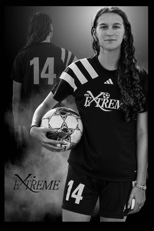 Soccer player wearing jersey number 14 holds game ball in dramatic black and white portrait.