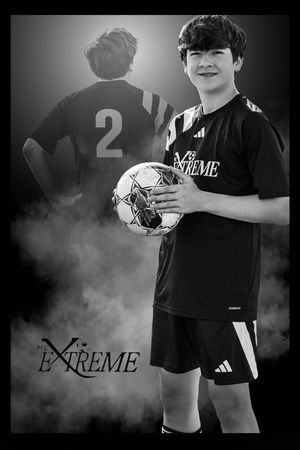 Athletic soccer player holds white ball against foggy black backdrop in black and white photo series.