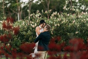 Wedding couple photographed through blooming spring trees and red foliage.