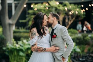 Romantic wedding couple sharing intimate moments in a garden setting with twinkling lights.