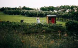 A small red shed sits near a pond surrounded by lush green countryside.