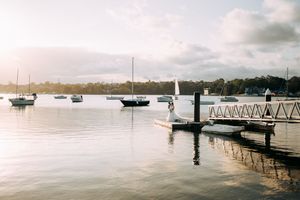 Sailboats anchored at a peaceful marina dock during sunset with calm waters reflecting the sky.