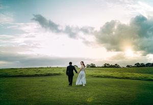 A panoramic view of rolling green hills and cloudy skies during a wedding photoshoot at sunset.