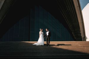 A dramatic architectural wedding photo with strong shadows on grand stone steps.