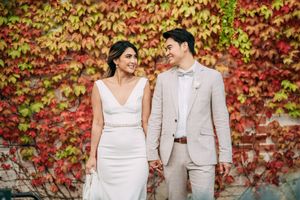 Wedding portraits against a wall covered in vibrant red autumn ivy leaves.