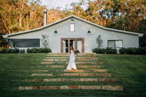 White ranch-style wedding venue with rustic wooden steps leading up the hillside.