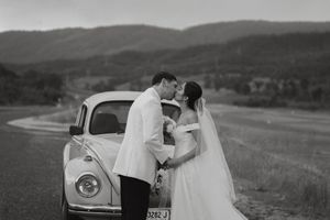 A classic vintage Volkswagen Beetle provides a romantic backdrop in a mountainous landscape.