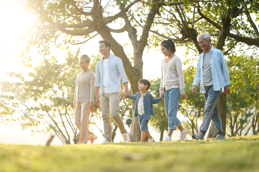 Family walking together in a sunlit park during golden hour creating a joyful outdoor moment in nature.