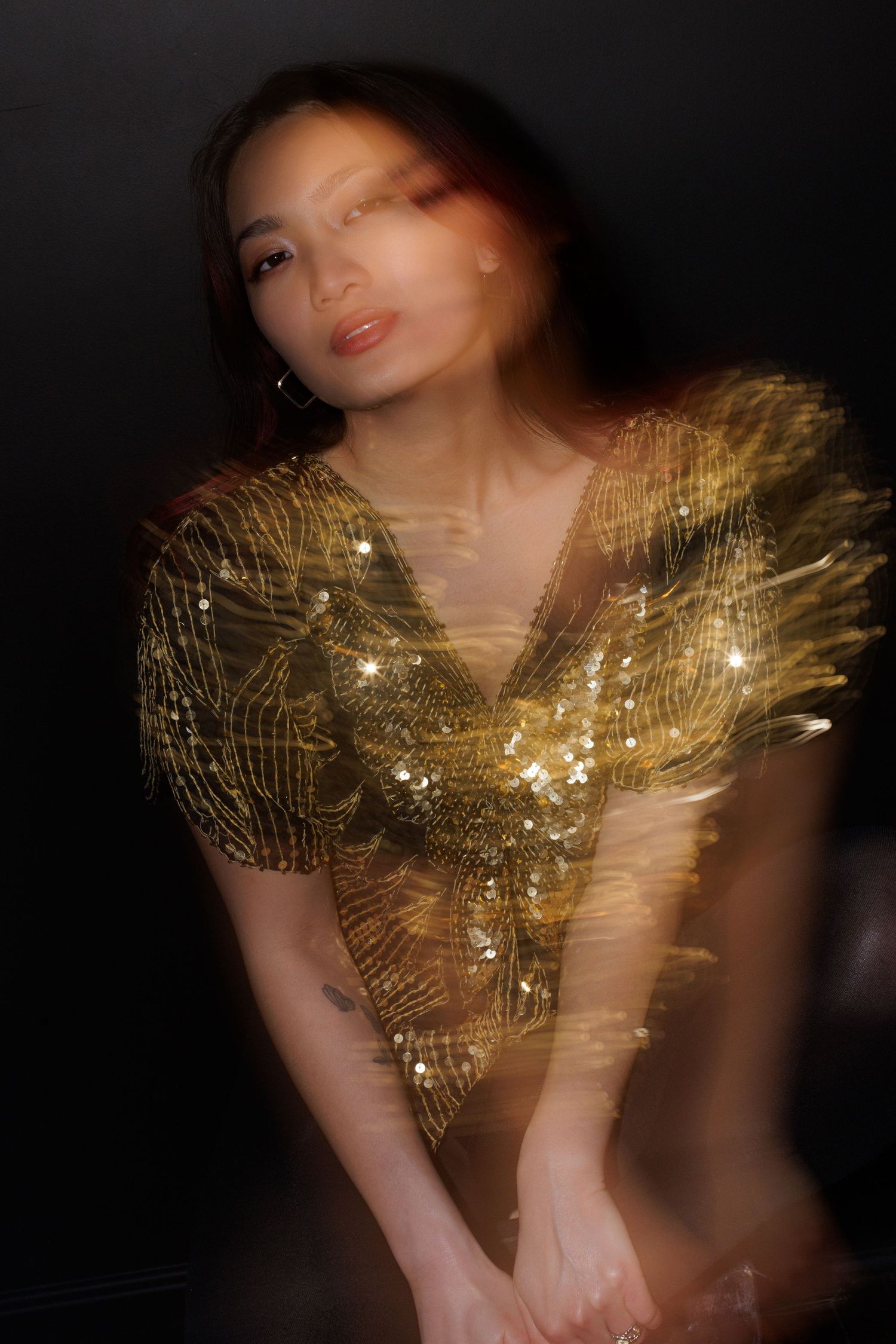 Soft focus portrait showcasing a metallic gold patterned top with dramatic lighting.