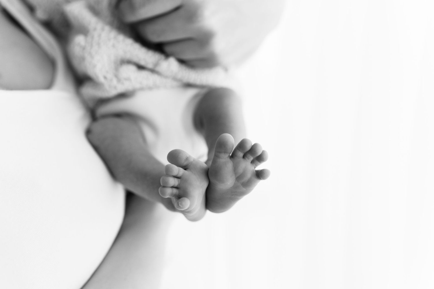 Black and white image of tiny baby feet with soft wrinkles and toes.
