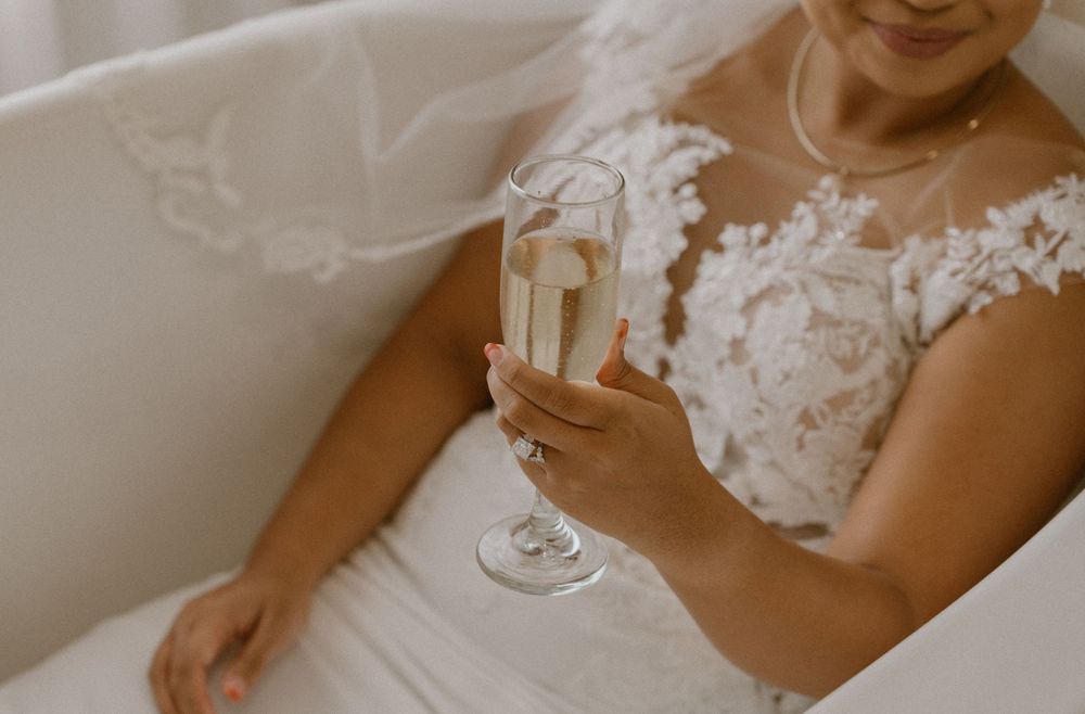Detail shot of a champagne glass held by someone in a lace wedding dress.