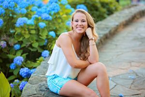A casual summer portrait on a stone path with blue hydrangeas in the background.