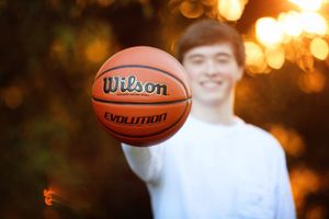 Wilson basketball floating in mid-air at sunset with blurred background.