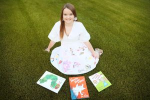 White dress portrait on green lawn displaying colorful artwork and illustrations.