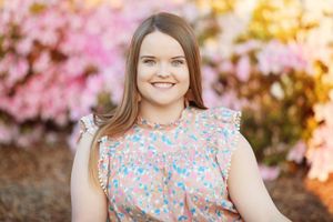 Spring portrait with cherry blossoms featuring floral print ruffled dress.