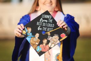 Decorated graduation cap with Disney characters and quote displayed against blue graduation gown.