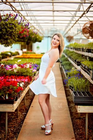 A joyful greenhouse portrait surrounded by colorful flowers and hanging baskets.